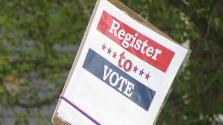 Una persona muestra un cartel para registrarse a votar.