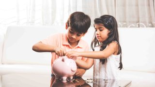 Niños ahorrando monedas en la alcancía en casa.