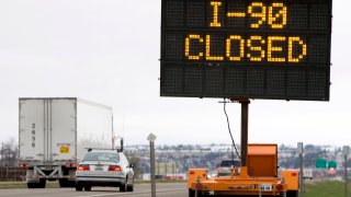 Traffic travels past a reader board indicating the closure of Interstate 90 at the Montana-Wyoming border