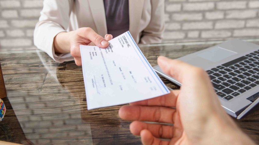 Close-up Of A Business Woman Giving Cheque To Her Colleague At Workplace In Office