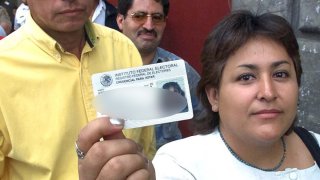 Una mujer muestra su credencial de elector, mientras espera formada para emitir su voto en una casilla especial ubicada a un costado del Zocalo de la ciudad de Mexico el 02 de julio de 2000.