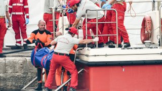 Buzos del cuerpo de bomberos de Italia suben a bordo una bolsa de plástico con el cuerpo de una de las víctimas de un naufragio, en Porticello, Sicilia, en el sur de Italia, el jueves 22 de agosto de 2024.