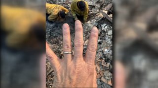 Firefighters help Altadena resident Victoria Desantis find her wedding band after the Eaton Fire destroyed her home.