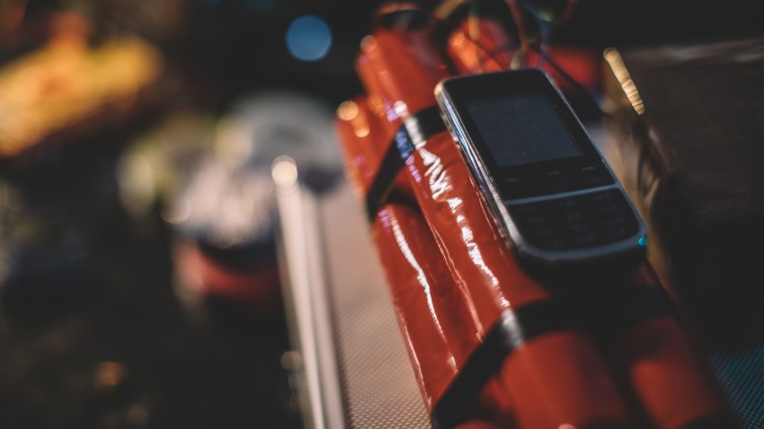 Dynamite bomb with mobile phone attached to it in workshop, no people.