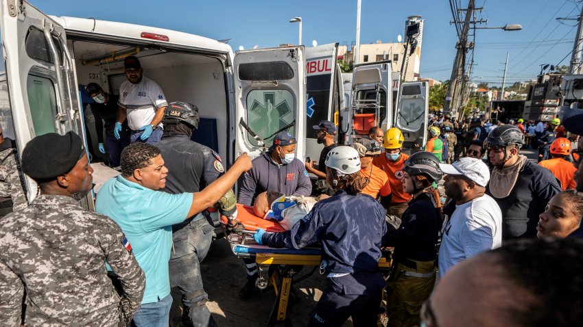 TOPSHOT – Members of Civil Defence and firefighters carry a wounded man following the collapse of the Jet Set nightclub roof, in Santo Domingo, on April 8, 2025. At least 27 people were killed when the roof of a nightclub in the Dominican Republic collapsed early Tuesday morning, emergency services said, with rescue operations still underway. (Photo by Francesco SPOTORNO / AFP) (Photo by FRANCESCO SPOTORNO/AFP via Getty Images)