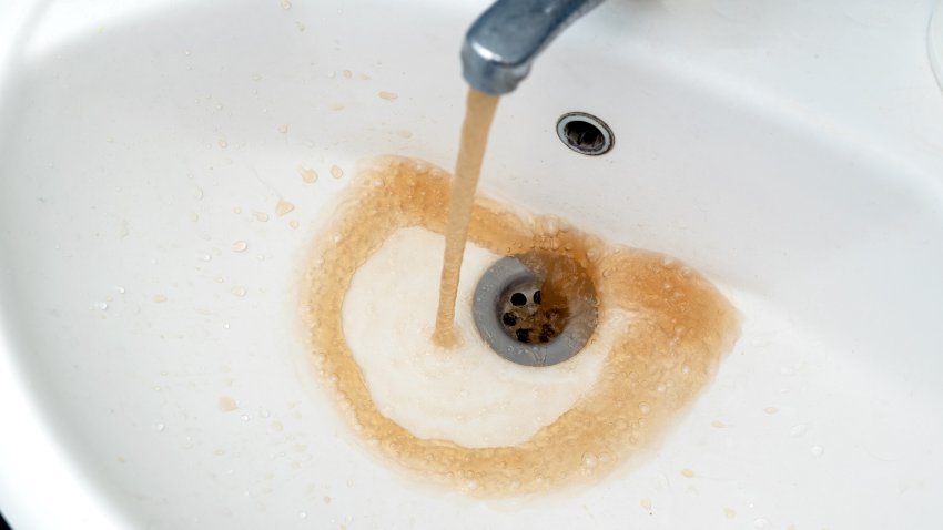 Dirty water from the tap. Rusty water flows into a white sink from a faucet. selective focus
