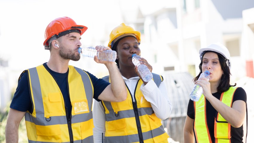 Healthy worker engineer team thirsty drinking clean water in hot temperature weather summer season for fresh relax at construction site workplace.