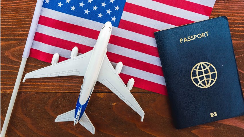 Flag of United States with port and toy airplane on wooden background. Flight travel concept